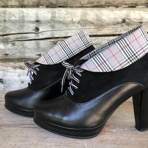 May include: Black heeled boots with a plaid fabric detail around the ankle.