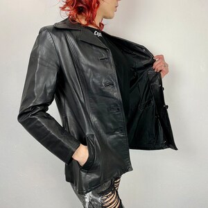 May include: A black leather jacket with a button closure and two pockets. The jacket is unzipped and the lining is visible.