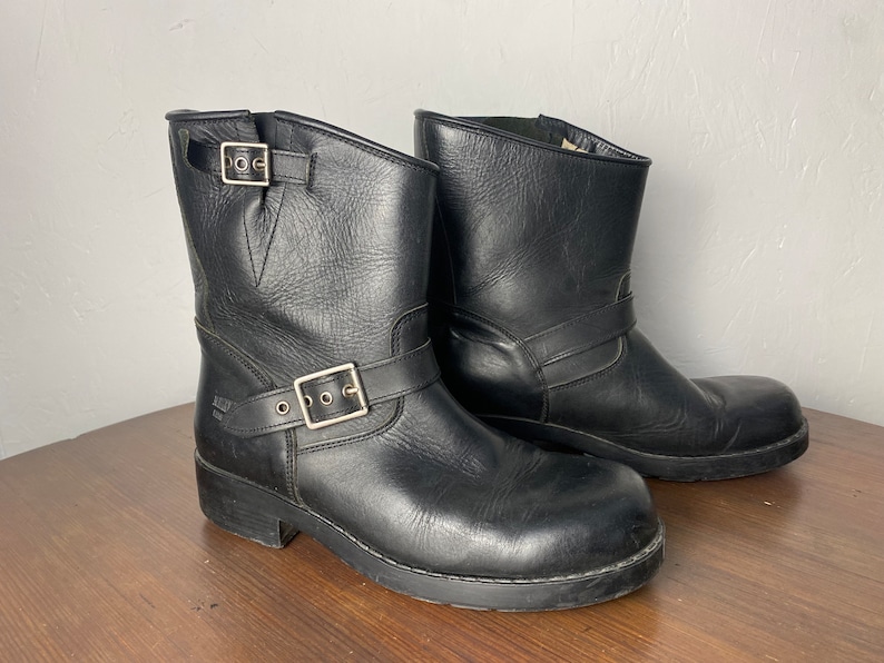 May include: A pair of black leather ankle boots with buckles. The boots have a rounded toe and a chunky heel.