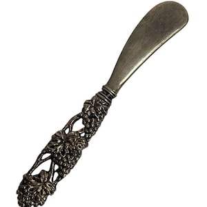 May include: Silver butter knife with a detailed grapevine handle.