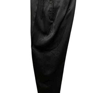 May include: Black satin pants with a high waist and button-up closure. The pants have a pleated front and a wide leg design. The fabric has a slight sheen, giving the pants a formal appearance.