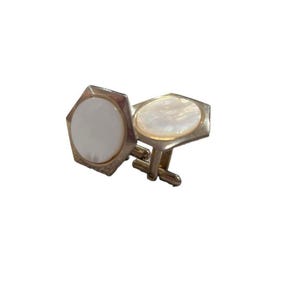 May include: A pair of silver cufflinks with white mother-of-pearl insets. The cufflinks are hexagonal in shape.
