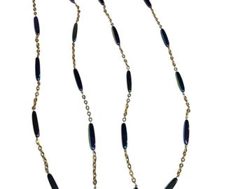 May include: A long gold chain necklace with iridescent blue oval-shaped beads.