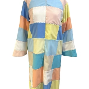 May include: A long, patchwork robe with a zipper closure. The robe is made of different colored squares of fabric, including blue, pink, yellow, and white.