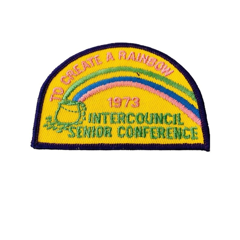 K&ouml;nnte beinhalten: Ein gelber gestickter Aufn&auml;her mit einem Regenbogen, einem Topf und dem Text "To Create A Rainbow 1973 Intercouncil Senior Conference".