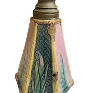 May include: A ceramic lamp base with a pink, green, and yellow bamboo design. The base has a brass top with a hole for a light bulb.