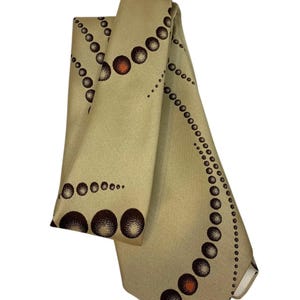 May include: A beige silk tie with a pattern of brown and orange circles. The tie has the text "DON LOPER" on the tag.