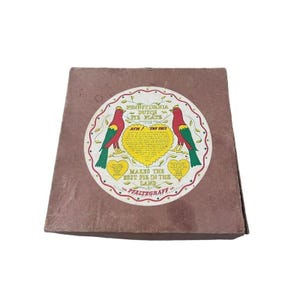 May include: A brown cardboard box with a round sticker featuring two red and green birds with yellow hearts and the text "Pennsylvania Dutch Pie Plate. Ach! Try This! Makes the best pie in the land. The Pfaltzgraff Co."