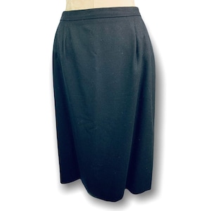 May include: A black, knee-length skirt. The skirt is made of a solid, dark fabric and has a simple, classic design. The skirt is displayed on a mannequin.