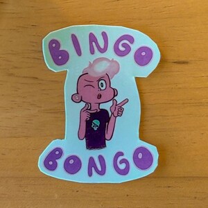 Könnte beinhalten: Ein gestanzter Aufkleber mit hellblauem Hintergrund, der eine Zeichentrickfigur mit rosa Haut und Haaren zeigt, die ein dunkelviolettes T-Shirt mit einem kleinen Totenkopf-Motiv trägt. Der Text BINGO steht in Violett darüber und BONGO darunter.