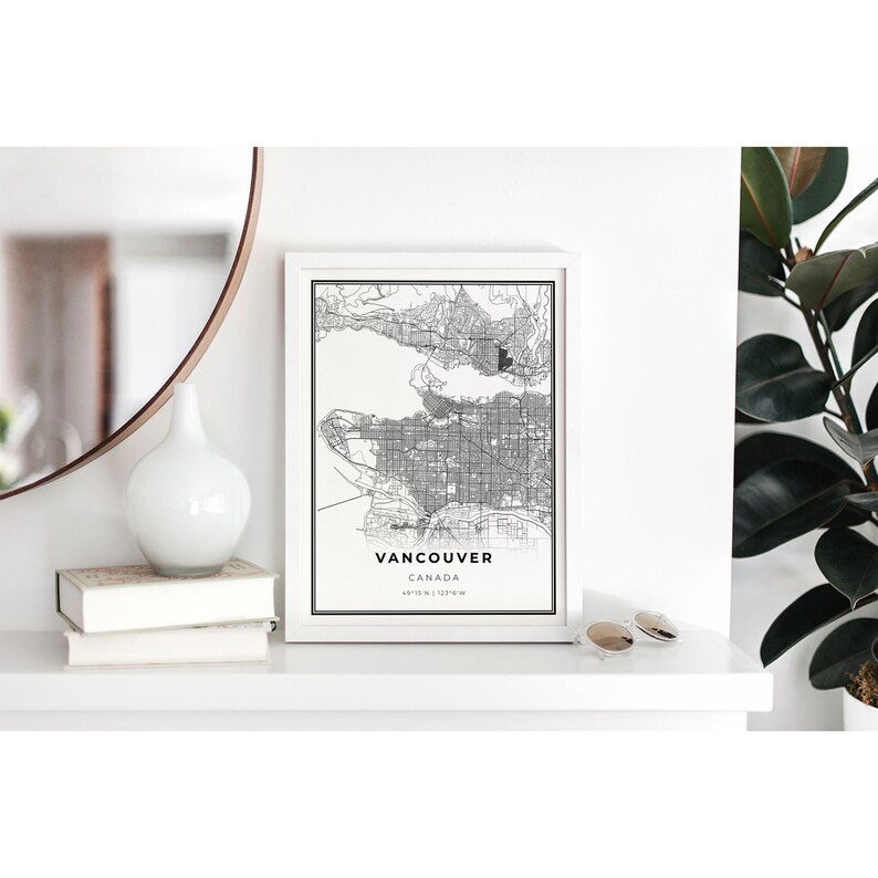 May include: A black and white map print of Vancouver, Canada, in a white frame. The map shows the city streets and surrounding area. The text "Vancouver, Canada" and the coordinates "49&deg;16' N 123&deg;6' W" are printed below the map.