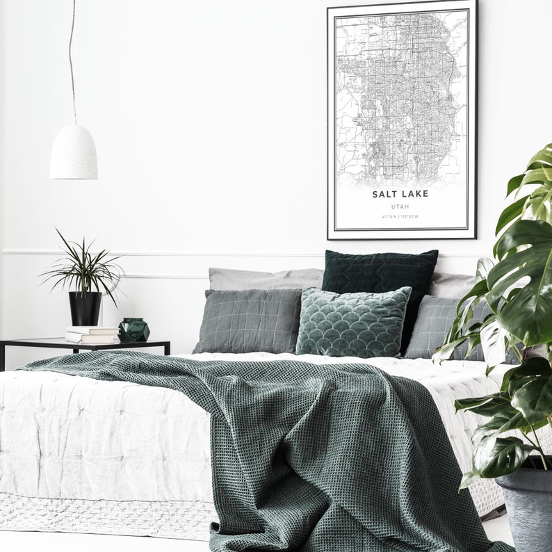 Puede incluir: Una cama blanca con una manta de tejido de waffle verde y una variedad de almohadas. Las almohadas son grises, verde oscuro y verde claro. Un mapa en blanco y negro de Salt Lake City, Utah est&aacute; colgado en la pared sobre la cama. Una planta en maceta est&aacute; a la derecha de la cama.