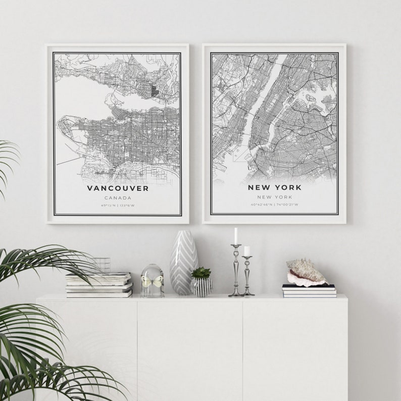 May include: Two black and white city maps in white frames. The map on the left is of Vancouver, Canada, and the map on the right is of New York City, New York.