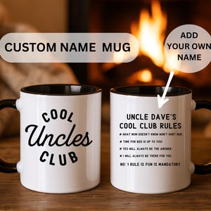 May include: Two white ceramic mugs with black handles and rims. One mug reads "COOL Uncles CLUB" in black script. The other mug has "UNCLE DAVE'S COOL CLUB RULES" printed on it, with a list of rules. The text "CUSTOM NAME MUG" is above the mugs.