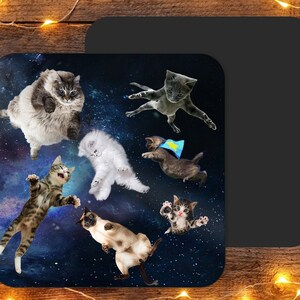 Peut inclure: Une illustration colorée de sept chats flottant dans l'espace sur un fond bleu foncé avec des étoiles. Les chats sont dans différentes poses, dont un portant une cape de super-héros.