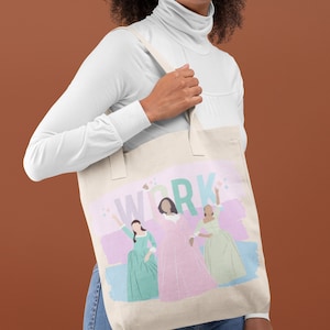 Op de afbeelding: Een witte canvas tote bag met een roze, groene en blauwe print met drie vrouwen en het woord "WORK" in grote, kleurrijke letters.