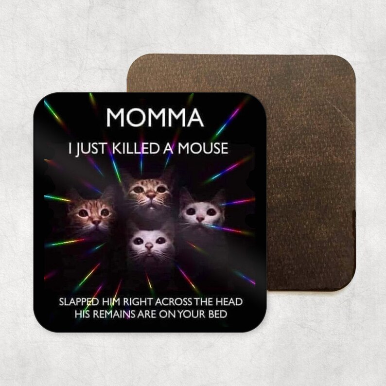May include: A black and white square coaster with a cat meme. The text reads "Momma I just killed a mouse. Slapped him right across the head. His remains are on your bed."