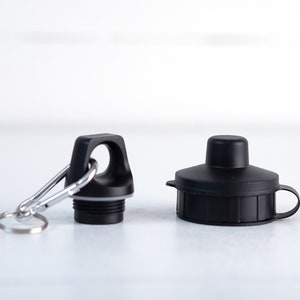 May include: Two black bottle caps, one with a loop and a carabiner clip, the other with a small handle.
