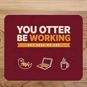 May include: A rectangular maroon mouse pad featuring the white and yellow text "YOU OTTER BE WORKING" followed by "BUT HERE WE ARE" on a yellow banner. Below the text are white line art icons of an otter, a laptop, and a steaming coffee mug.