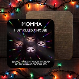 May include: A black and white coaster with a humorous cat meme. The text reads "Momma I just killed a mouse. Slapped him right across the head. His remains are on your bed."