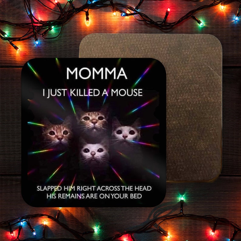 May include: A black and white coaster with a humorous cat meme. The text reads "Momma I just killed a mouse. Slapped him right across the head. His remains are on your bed."