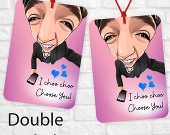 Könnte beinhalten: Doppelseitiger Auto-Lufterfrischer mit einem Cartoon-Bild einer Person. Die Vorderseite zeigt "I choo choo Choose You!" mit blauen Herzen. Die Rückseite hat das gleiche Bild und den gleichen Text.
