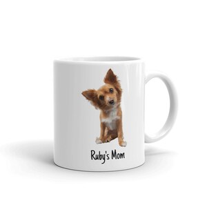 May include: White ceramic coffee mug featuring a brown and white chihuahua dog looking over its shoulder. The text "Ruby's Mom" is printed on the mug.