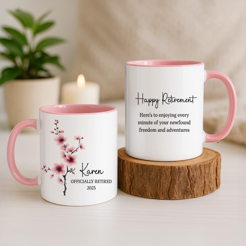 May include: Two white ceramic mugs with pink interiors and handles. One mug features a floral design and the name "Karen" with "OFFICIALLY RETIRED 2025." The other mug says "Happy Retirement" with a celebratory message.