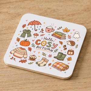 May include: A square white coaster featuring a colourful autumn-themed illustration with the text "Hello COSY AUTUMN". The design includes a pumpkin, jumper, scarf, umbrella, books, mug, ghost, hedgehog, candle, boots, socks, blanket, and leaves.