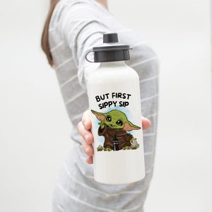 May include: White water bottle with a green and brown cartoon character holding a smaller water bottle. The text "BUT FIRST SIPPY SIP" is printed on the bottle.