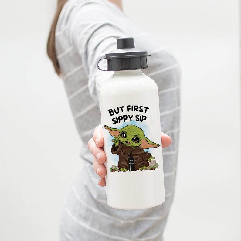 May include: White water bottle with a green and brown cartoon character holding a smaller water bottle. The text "BUT FIRST SIPPY SIP" is printed on the bottle.