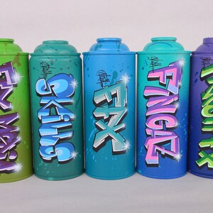 May include: Five spray paint cans with different colors and graffiti designs. The cans are labeled "FX Mafia", "Skulls", "FX", "Fingaz", and "Fresh FX".