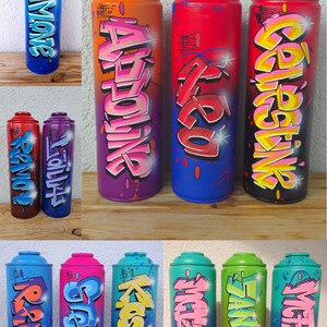 May include: Ten spray paint cans with different names written in graffiti style. The names are Simone,  Adrienne,  Zazu,  Gabriela,  King,  Stern,  Koslov,  Michelza,  Sangrid, and Victoria. The cans are arranged in two rows of five.