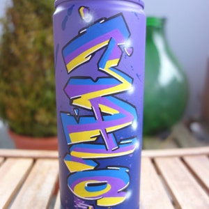 May include: A purple spray paint can with a yellow, blue, and purple graffiti design. The design features the word "LOVE" in stylized lettering.