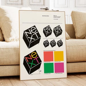 May include: A framed specification sheet featuring the "NeXT" logo in various sizes and colors. The logo is a black cube with the letters "NeXT" in white, yellow, green, pink, and red. The sheet also includes color swatches and a 28-degree angle measurement.