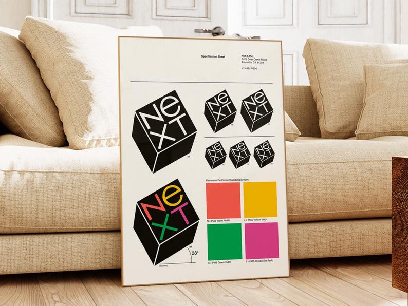 May include: A framed specification sheet featuring the "NeXT" logo in various sizes and colors. The logo is a black cube with the letters "NeXT" in white, yellow, green, pink, and red. The sheet also includes color swatches and a 28-degree angle measurement.