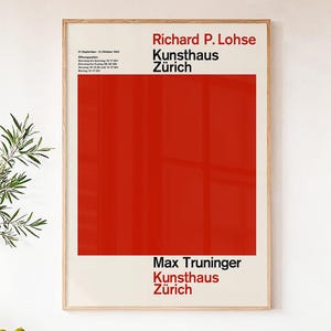 May include: A framed art print with a striking red rectangular design on a cream backdrop. The print displays the text "Richard P. Lohse Kunsthaus Zürich" and "Max Truinger Kunsthaus Zürich" in black and red. The artwork is mounted on a white wall.