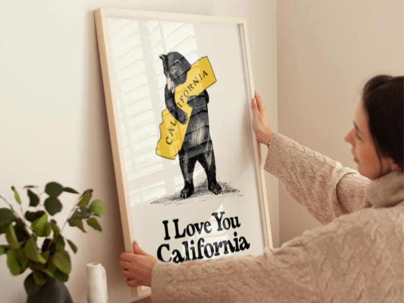 May include: A framed print featuring a black bear hugging a yellow outline of the state of California. The text "I Love You California" is printed below the bear.
