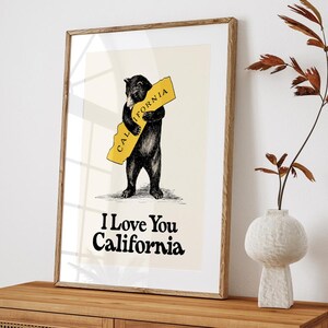 May include: A black bear hugging a yellow outline of the state of California with the text "CALIFORNIA" on it. The text "I Love You California" is below the bear.