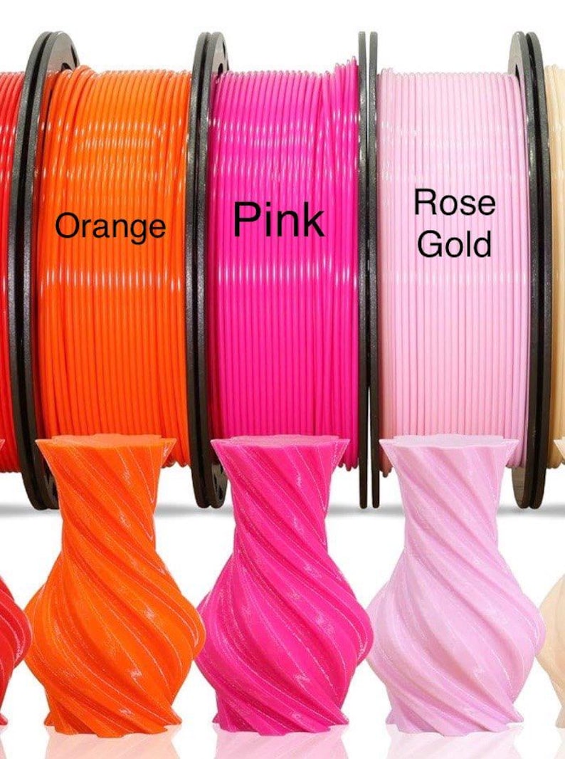 May include: Spools of orange, pink, and rose gold 3D printing filament are displayed above matching twisted vase-shaped objects. The spools are labeled with their respective colors. The vases have a spiral design.