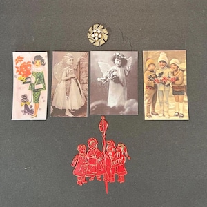 May include: A collection of vintage Christmas-themed ephemera, including postcards and a red die-cut ornament. The postcards feature images of children, angels, and a woman with a dog. A gold-tone brooch with white pearl accents is also included.