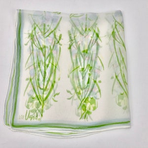 Peut inclure: Un foulard blanc transparent avec un motif floral vert. Le foulard a une bordure vert clair et la signature "Usna" dans le coin. Le motif floral présente des tiges et des feuilles vertes avec des touches de rose et de violet.