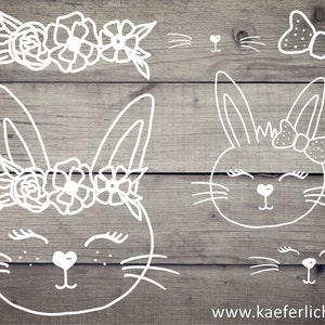 May include: Two white outline drawings of bunnies with closed eyes. One bunny is wearing a flower crown and the other is wearing a bow. The drawings are on a wood background.