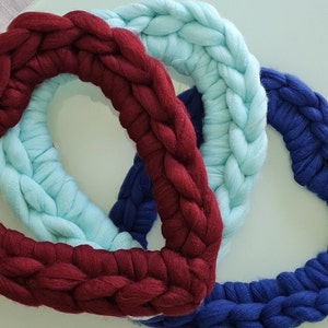 Puede incluir: Tres coronas tejidas en forma de coraz&oacute;n en color burdeos, azul claro y azul marino.