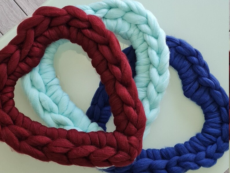 Puede incluir: Tres coronas tejidas en forma de coraz&oacute;n en color burdeos, azul claro y azul marino.