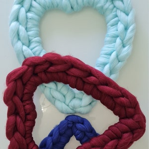 Puede incluir: Tres coronas de coraz&oacute;n de lana tejidas en colores azul, rojo y azul oscuro. Las coronas est&aacute;n apiladas con la corona azul en la parte superior, la corona roja en el medio y la corona azul oscuro en la parte inferior.