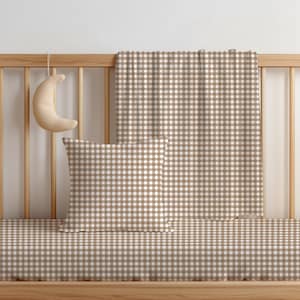 May include: A square throw cushion and a rectangular blanket featuring a tan and white gingham check pattern. A crescent moon-shaped plush object hangs from the wooden cot railing, which is positioned behind the cushion and the blanket.