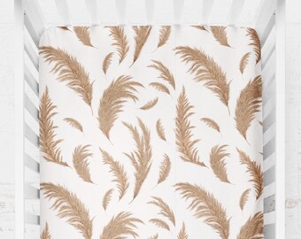 Peut inclure: Un drap-housse blanc pour lit bébé avec un motif de pampas en tan. Le drap est fait d'un tissu doux et respirant, idéal pour une chambre de bébé.