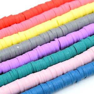 May include: A collection of colourful polymer clay beads in various shades of red, pink, yellow, grey, purple, green, pink, and blue. The beads are stacked in rows, creating a visually appealing pattern.