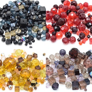 May include: Assortment of glass beads in various colours and shapes, including black, red, amber, and purple. The beads are ideal for jewellery making, crafting, and home decor.
